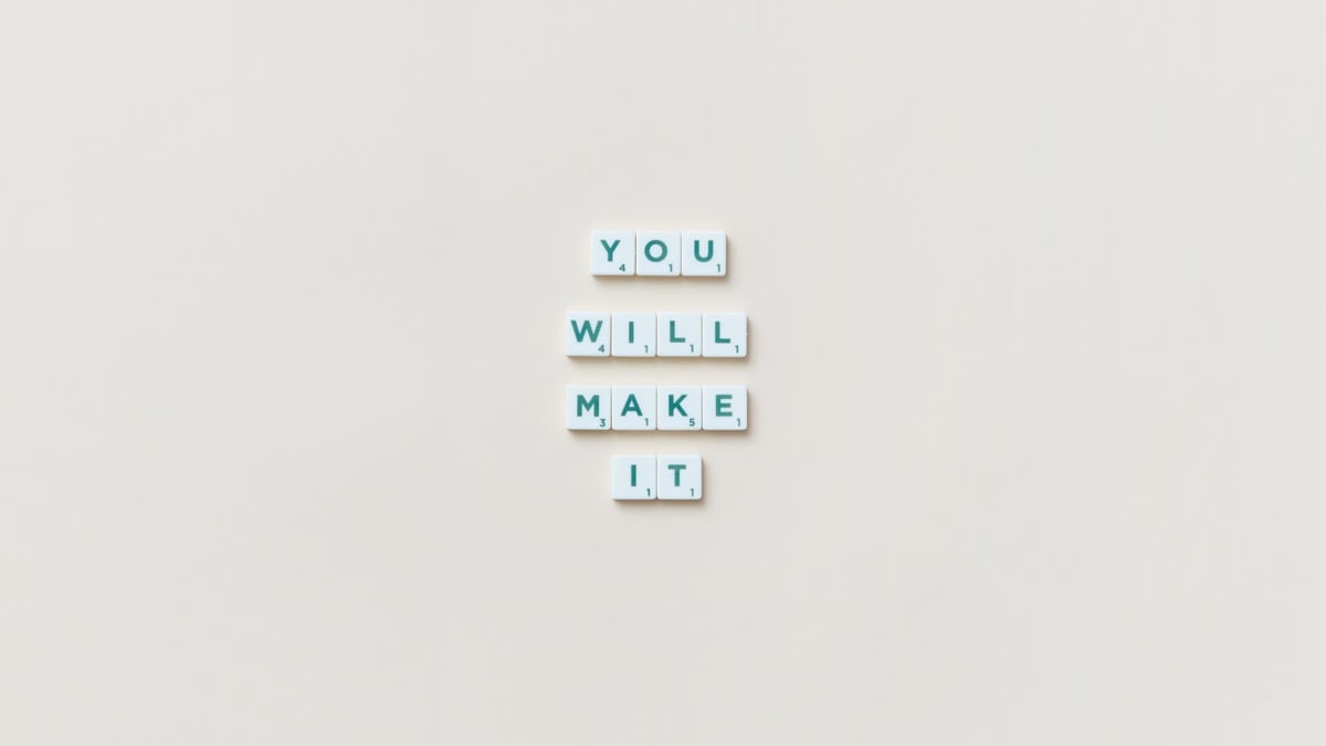 Motivational phrase 'You Will Make It' made from Scrabble tiles on a neutral background.